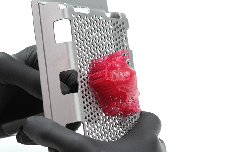 Abb. 6: Ablösen des gedruckten Objektes von der Bauplattform. Dieses sollte vorsichtig und gleichmäßig erfolgen. Für den NextDent 5100 gibt es einen Stempel, mit dem das Druckobjekt sehr gleichmäßig von unten gelöst werden kann.