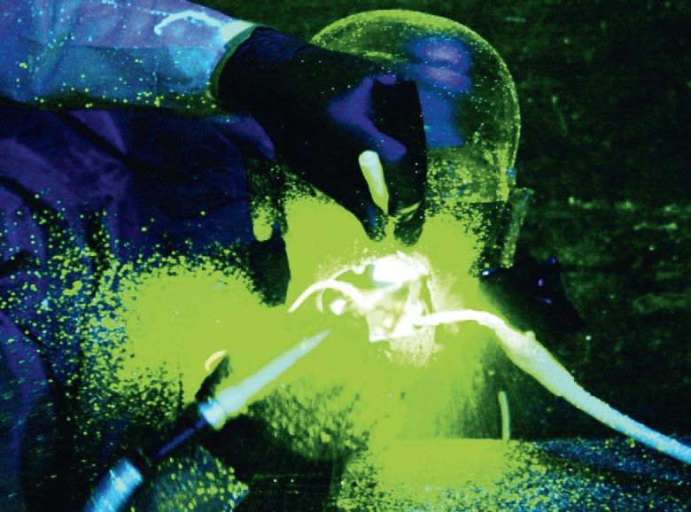Abb. 1: Aerosol und Spraynebelrückprallbildung im unmittelbaren Umfeld des Patientenmundes während der Anwendung eines maschinellen Scalers am Phantomkopf im verdunkelten Behandlungsraum. (Kühlmedium mit bei Schwarzlicht fluoreszierendem Natriumsalz versetzt nach digitaler Bearbeitung des Bildes mit einer Grafiksoftware).