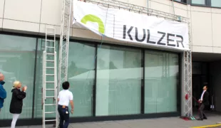Vor den Kulzer Mitarbeitern wurde das neue Logo an der Unternehmenszentrale von Akira Misawa, CEO von Kulzer (links) und von Osamu Hashimoto, Vorsitzender des Kulzer Aufsichtsrates (rechts), enthüllt. © Kulzer