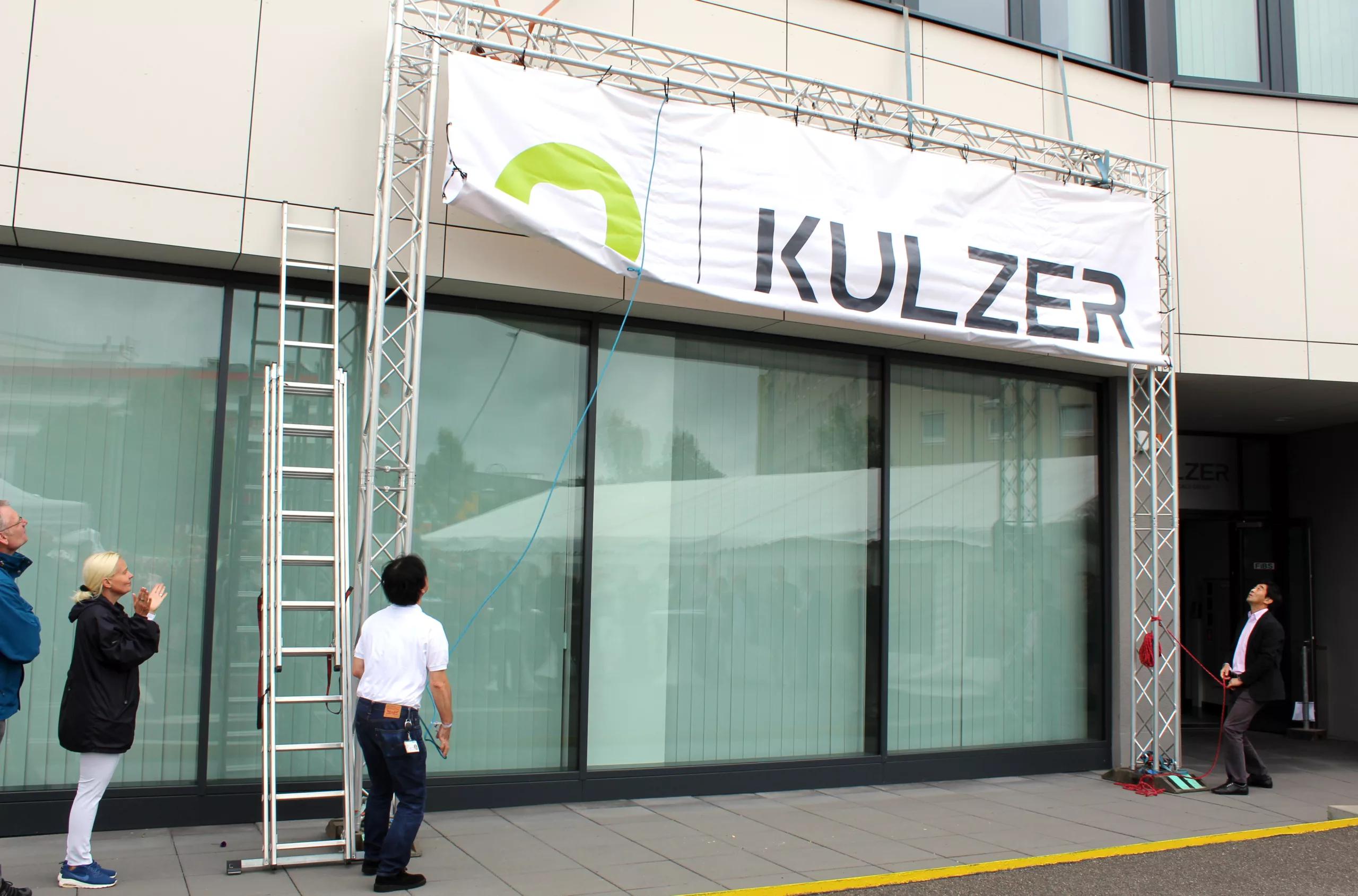 Vor den Kulzer Mitarbeitern wurde das neue Logo an der Unternehmenszentrale von Akira Misawa, CEO von Kulzer (links) und von Osamu Hashimoto, Vorsitzender des Kulzer Aufsichtsrates (rechts), enthüllt. © Kulzer