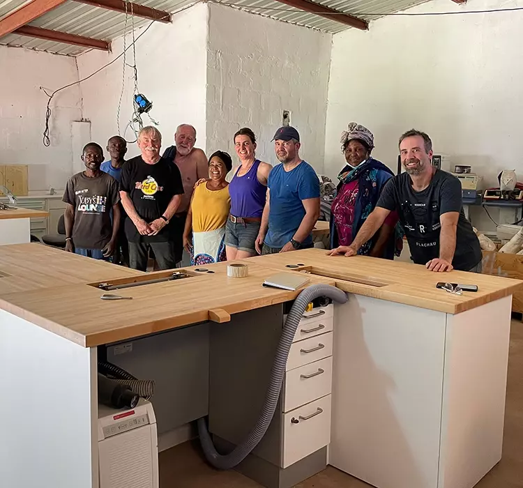 Abb.1: Aufbau des Lehrlabors für Mädchen in Mundulundulu (v.l.: Sam und Elliot, Dieter Baum, Bernd Bakendorf, Manka, Cornelia Fischer, Dr. Marco Mathys, Emily Striedl, Dr. Thomas Baum.)