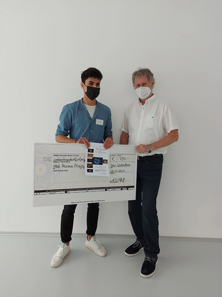 ZTM Jochen Peters übergibt das Preisgeld an den diesjährigen Sieger Abd Alazez Alajaj (Andreas Piorreck Zahntechnik, Leipzig).