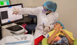 Ein Zahntechniker des Smile Train-Partners FISULAB in Kolumbien setzt die Primescan AC von Dentsply Sirona bei einem Spaltpatienten ein.