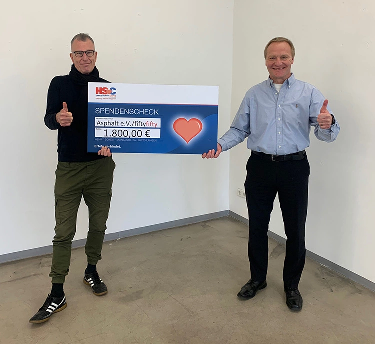 Detlev Fellmann, Gebietsverkaufsleiter NRW bei Henry Schein Dental Deutschland GmbH und Hubert Ostendorf vom Straßenmagazin fiftyfifty bei der Scheckübergabe.