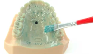 Abb. 1: Auftragen einer Schicht des 3D Isoliermittels auf ein Kunststoffmodell mit Bohrung für die Aufnahme des Dehnschraubenhalters.