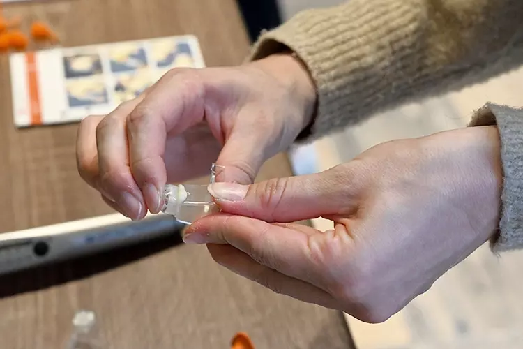 Überschussentfernung: Eine Teilnehmerin setzt eine mit 3M RelyX Universal Befestigungskomposit befüllte Krone auf einen Modellstumpf.