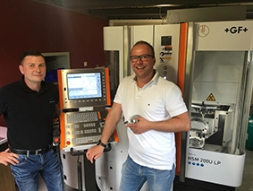 Jens Vogel (links), Anwendungsspezialist bei GF Machining Solutions und Tobias Fip, Gründer von Fip Zahnkunst GmbH vor der Fräsmaschine Mikron HSM 200U LP.