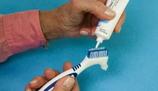 Abb. 1: Prothesenbürste und chlorhexidinhaltiges Mundpflege-Gel zum Reinigen von Zahnersatz.