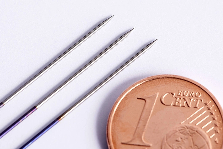 Bei der Entwicklung der PUKStar wurde unter dem Mikroskop mit chirurgischen Werkzeugen wie Nadelhaltern gearbeitet, da die kleinen WIG-Elektroden nur einen Durchmesser von etwa 0,6 bis 1,0 mm aufweisen. Auf diesem Bild ist ein Vergleich mit einer 1-Cent-Münze zu sehen.