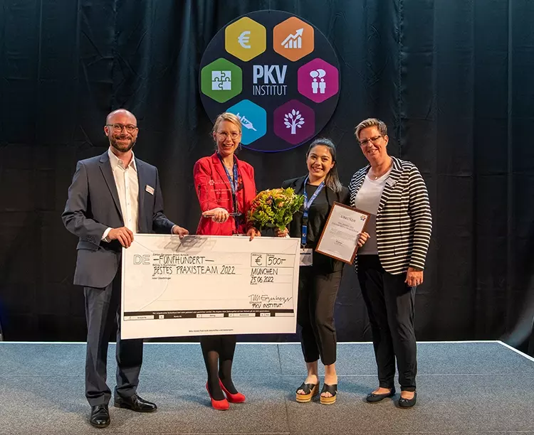 Dajana Schmidt und Eleni Kaloutsidou nahmen auf der Bühne des 15. Deutschen MFA-Tags & ZFA-Tags den ZFA-Award 2022 für ihr Team entgegen. V.l.n.r.: Tim Egenberger, Geschäftsführer des PKV Instituts, Dajana Schmidt, Eleni Kaloutsidou und Iris Schluckebier, Teilnehmerbetreuerin beim PKV Institut (Bildquelle: Thomas Cojaniz / PKV Institut).